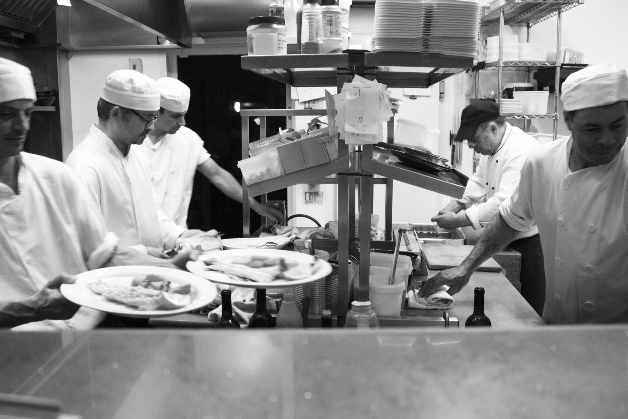 black and white image of chefs working on food preperations in the kitchen