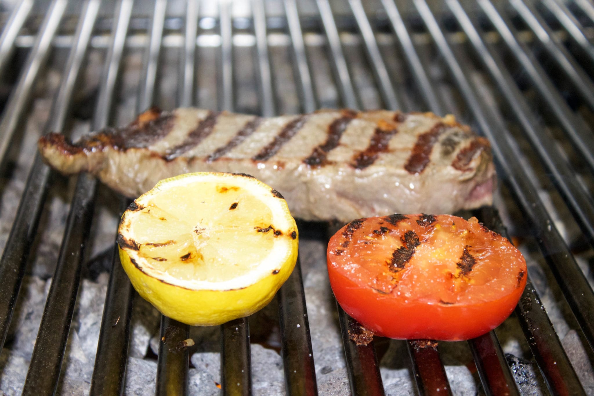 Steak on a grill with tomato and lemon